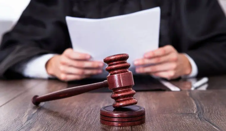 A judge 's gavel sitting on top of a wooden table.